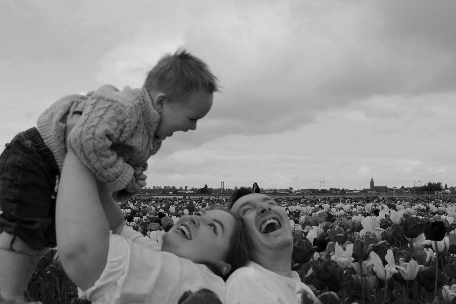 Tarryn and Pierre Blom laughing with their son in a field of flowers